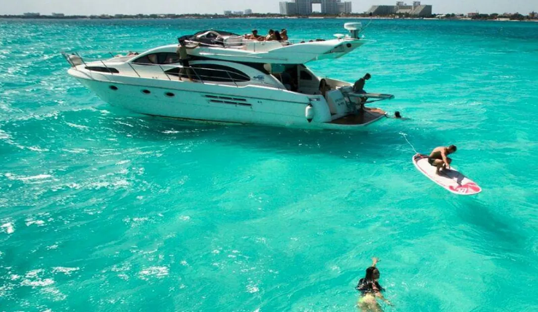 White Azimut yacht in turquoise water with a person on a paddleboard