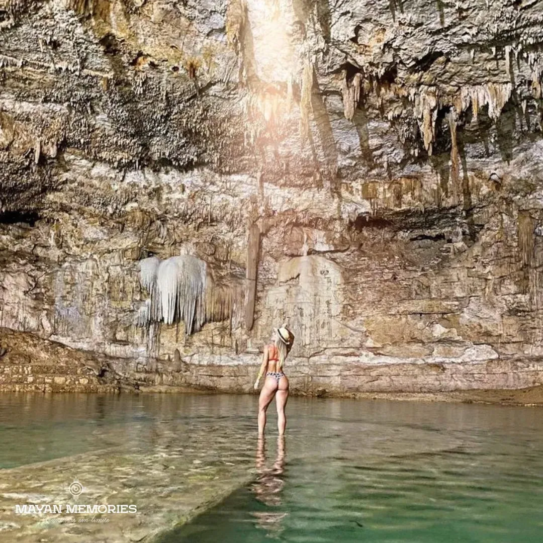 Visitor standing on the platform of a cave cenote under a beam of light