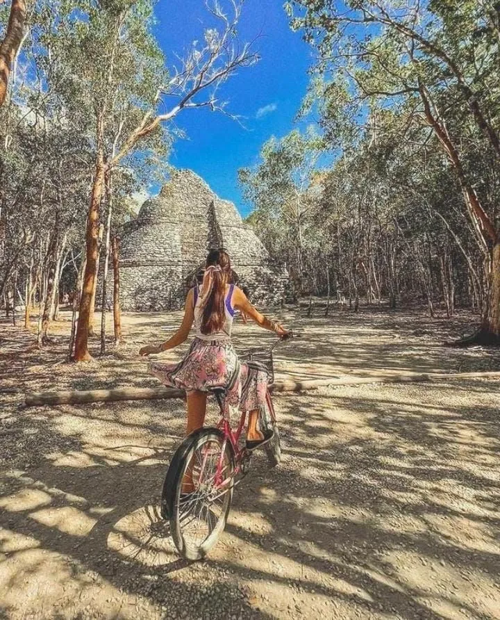 Woman riding a bicycle along a jungle path in Cobá