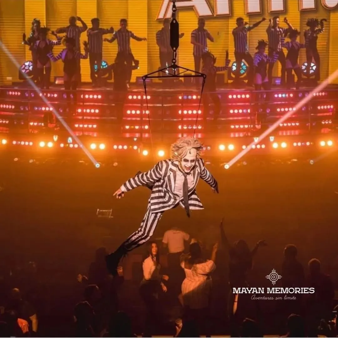 Performer in a striped suit on stage under orange lights