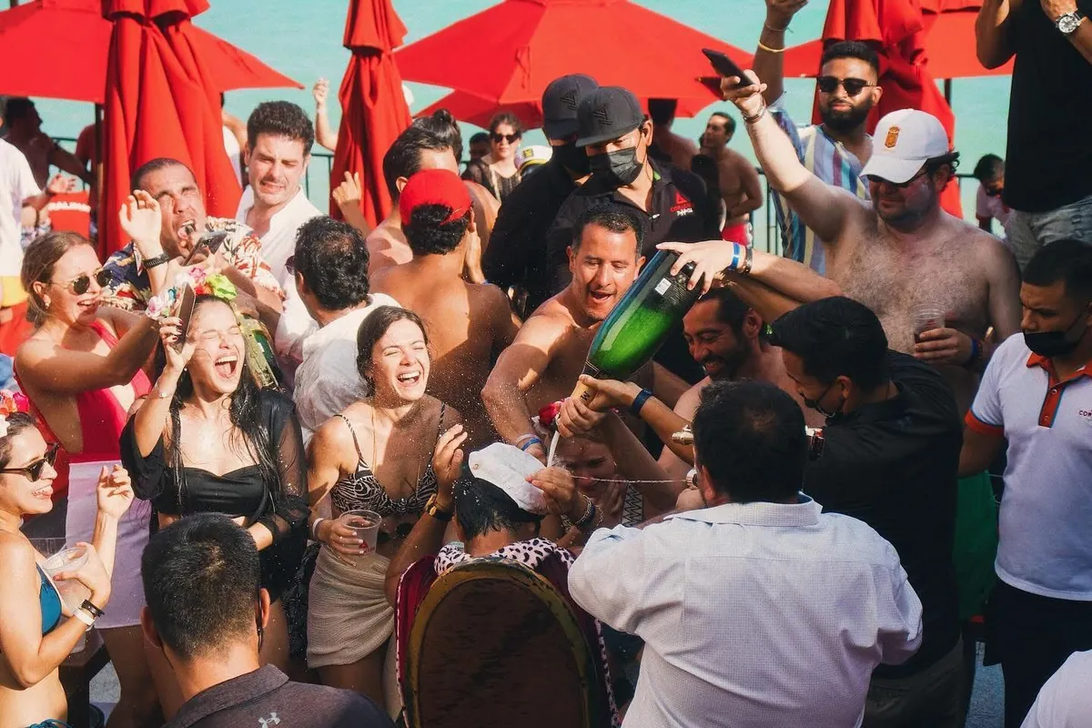 Crowd dancing under red umbrellas at the beach club