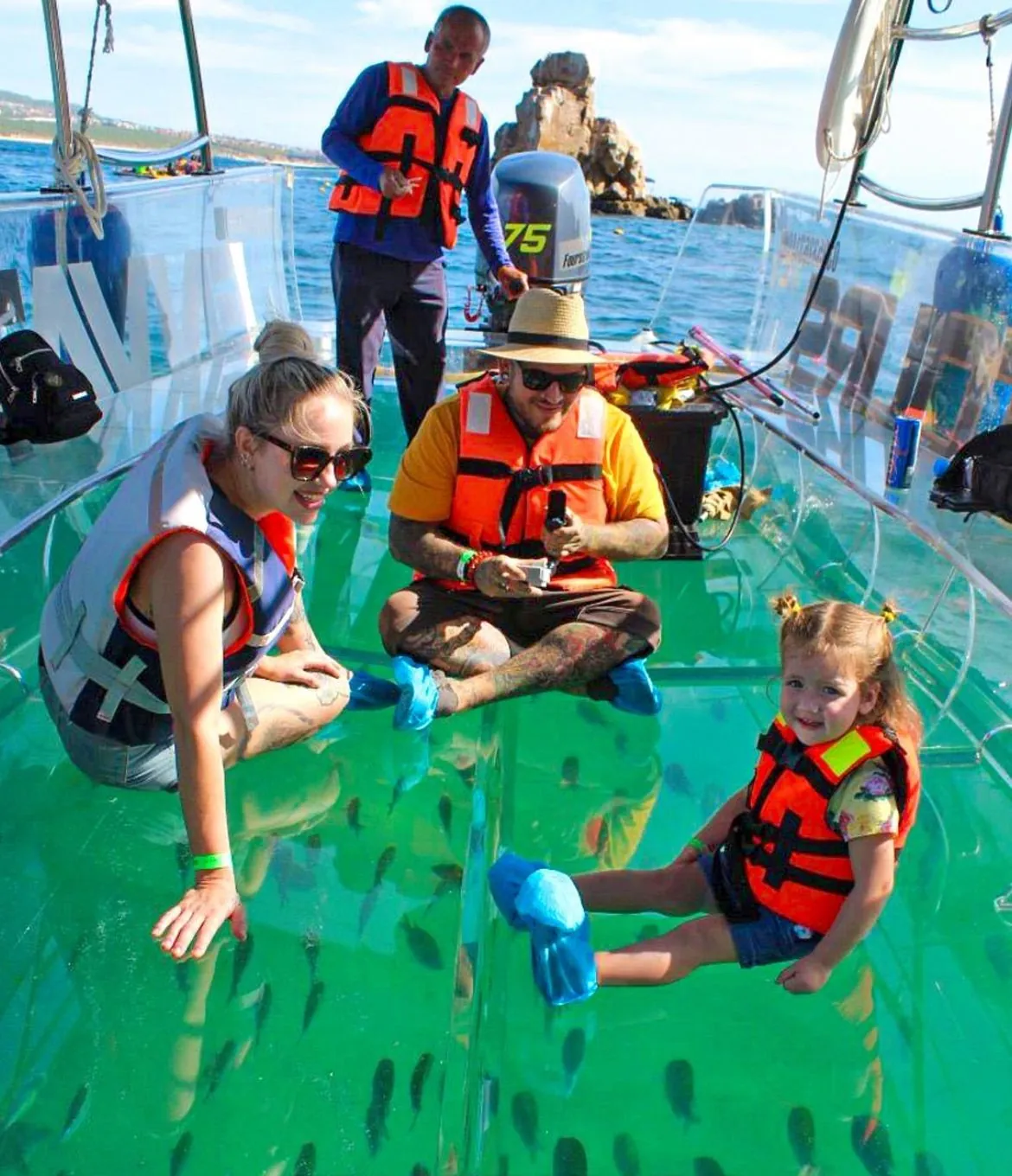 Family in life jackets sitting on the clear boat's transparent floor