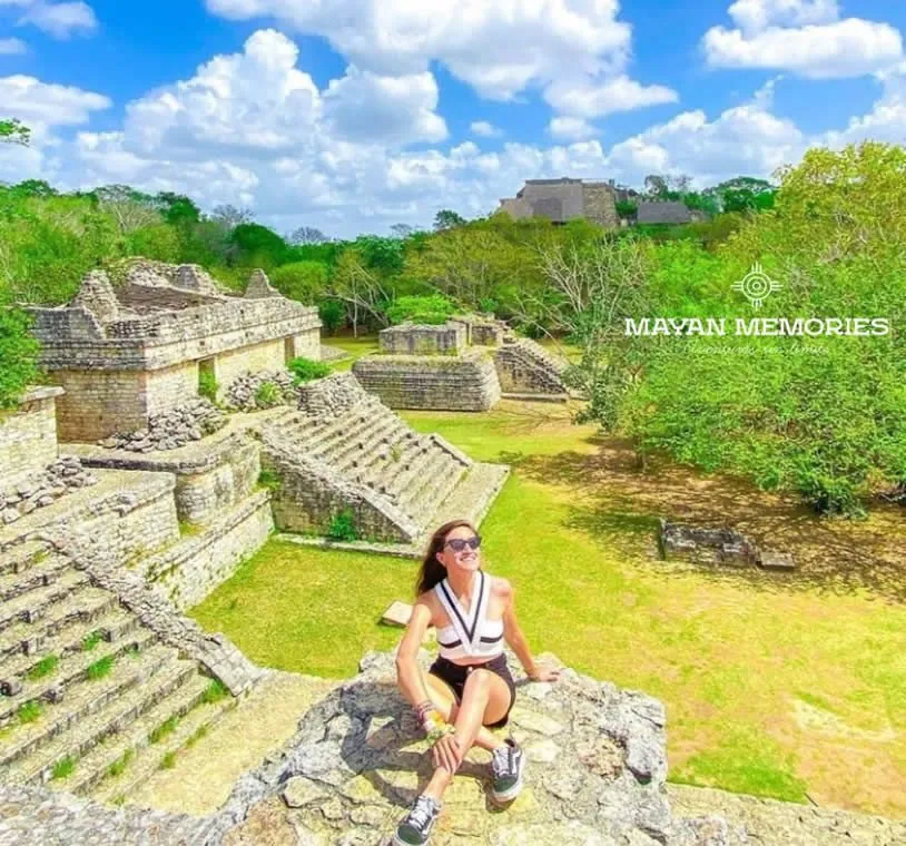 Woman sitting on the Ek Balam ruins surrounded by green lawn
