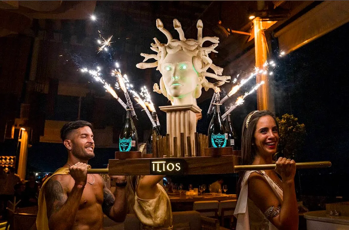 Waiters carrying a Medusa head with sparklers at Ilios