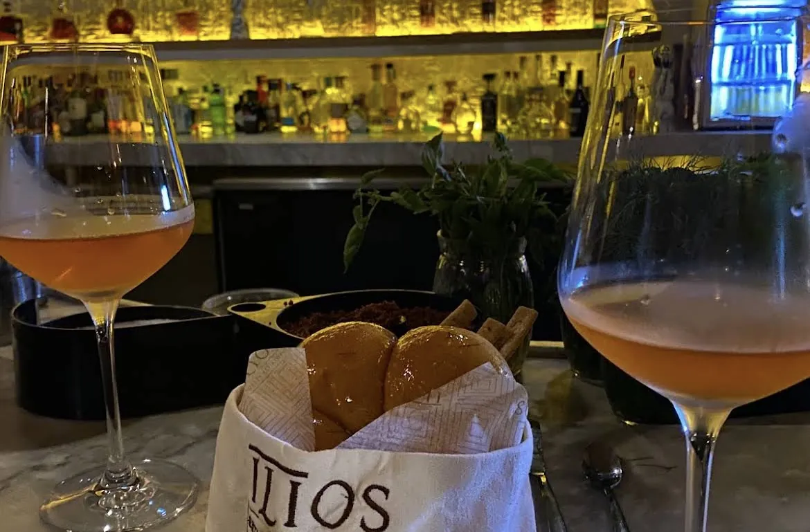 Cocktails and a bread basket with the Ilios logo