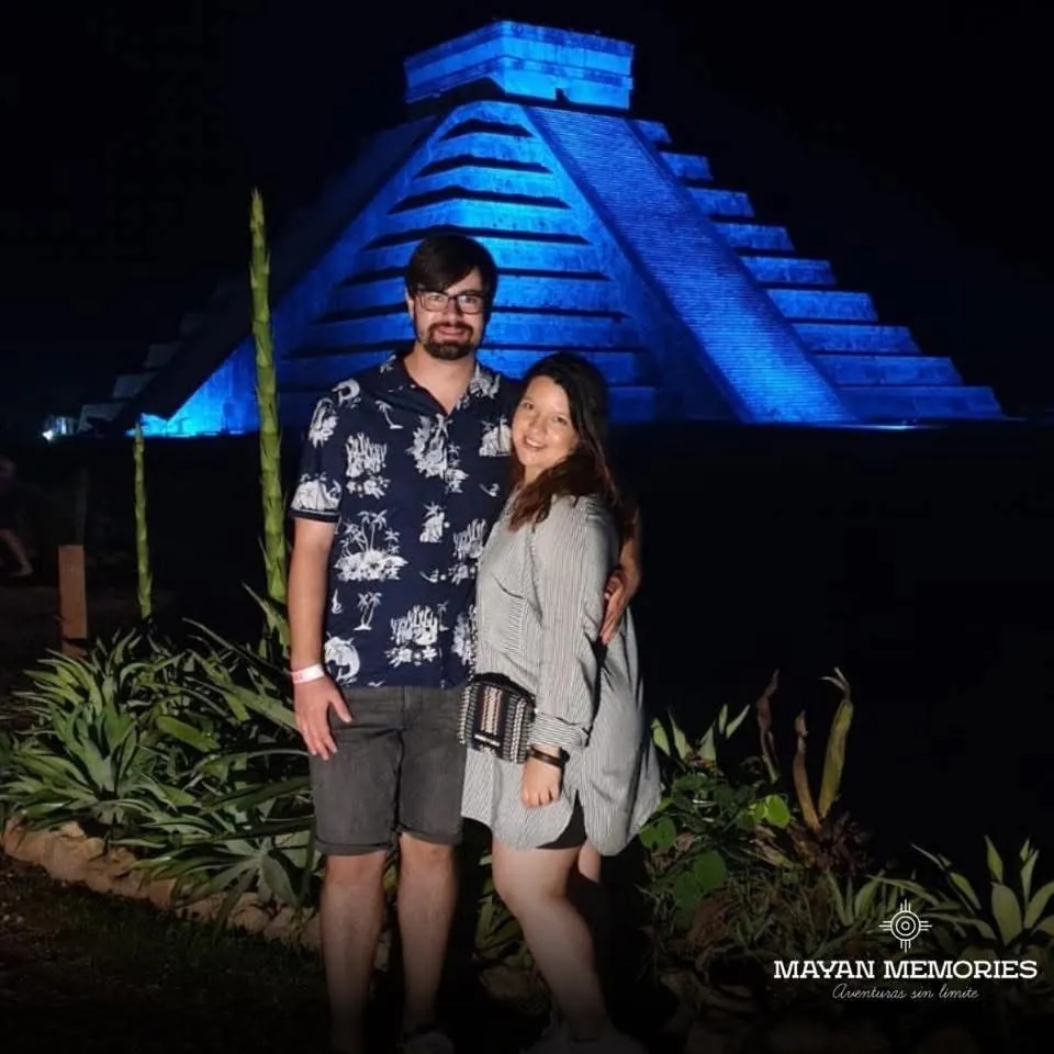 Couple in front of the pyramid lit in blue at night