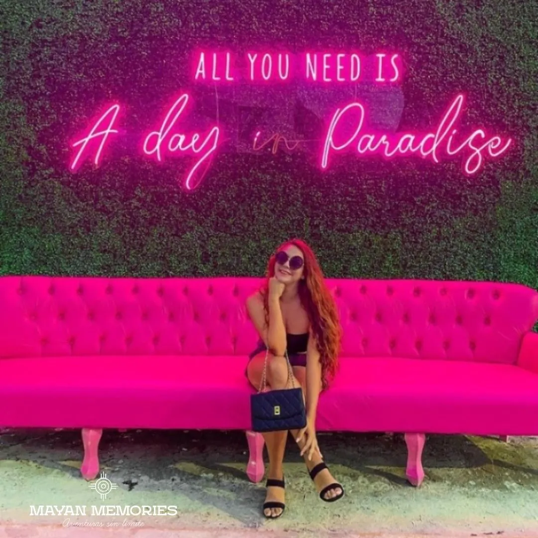 Woman on a pink sofa under a neon sign
