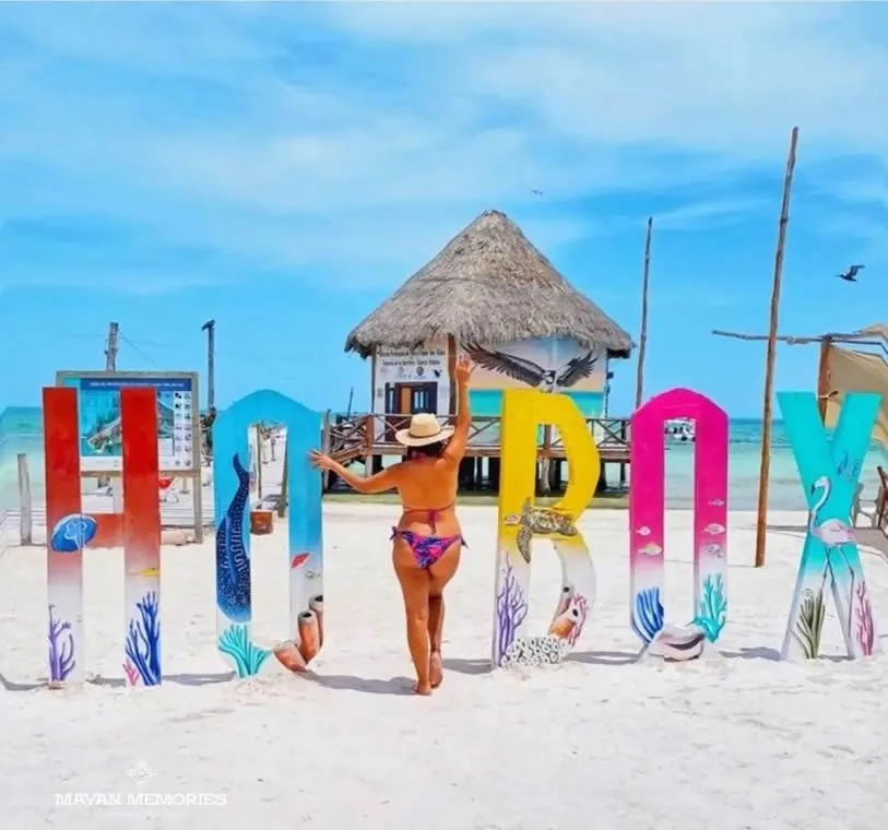 Woman walking past the colorful Holbox letters