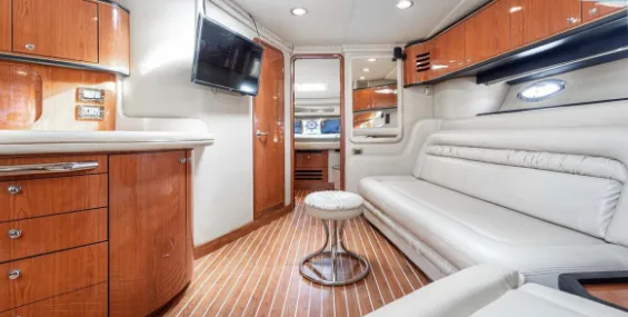 Yacht's interior lounge with a white sofa and TV