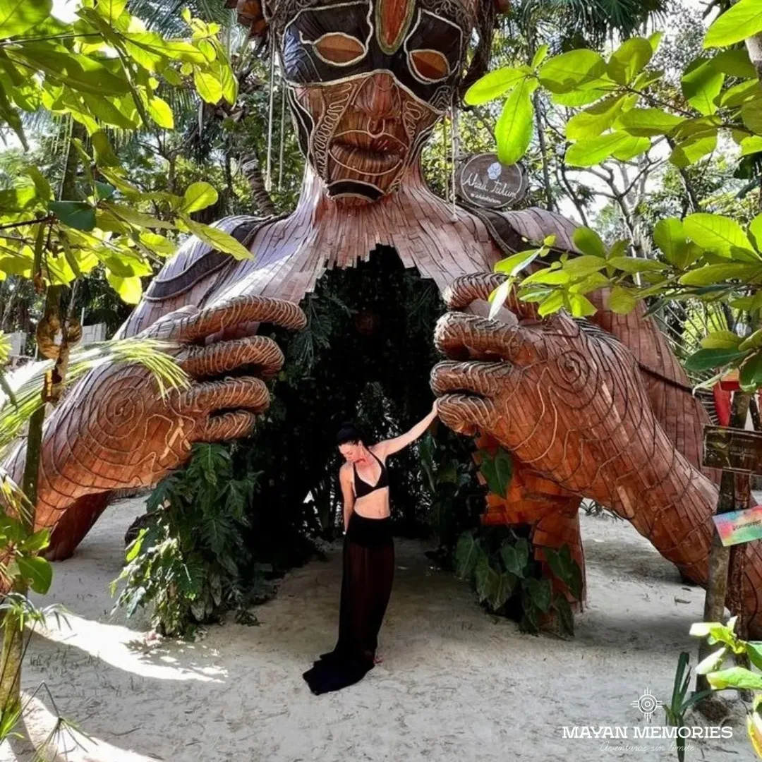 Visitor between the hands of the wooden Mother Nature sculpture