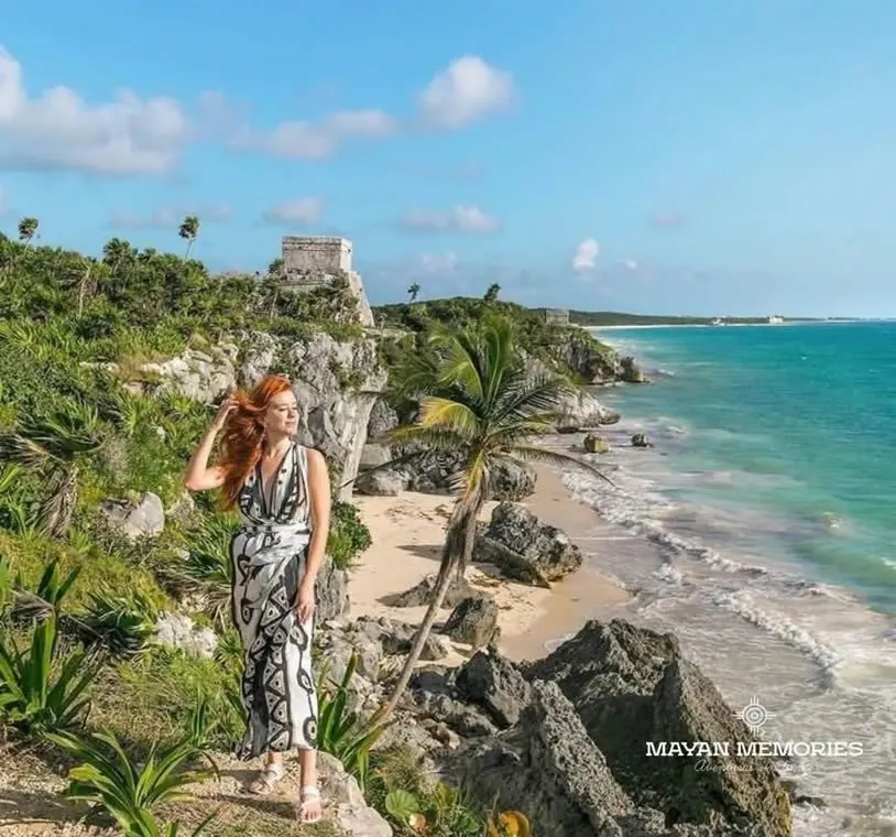 Woman on the Tulum cliff with the turquoise coast behind