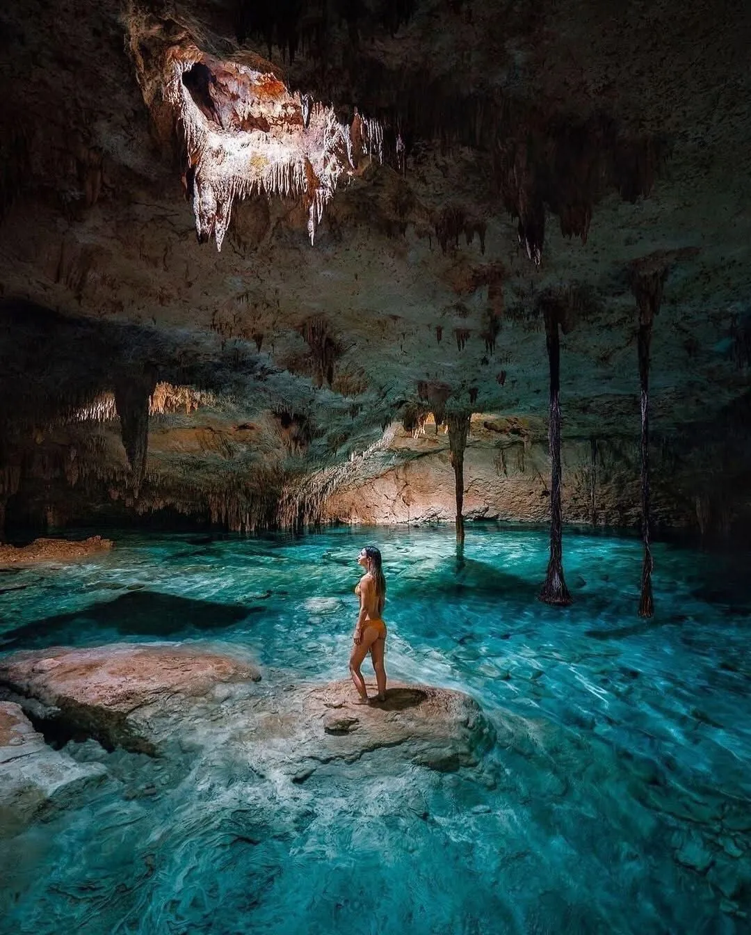 Woman standing in a cave cenote with stalactites