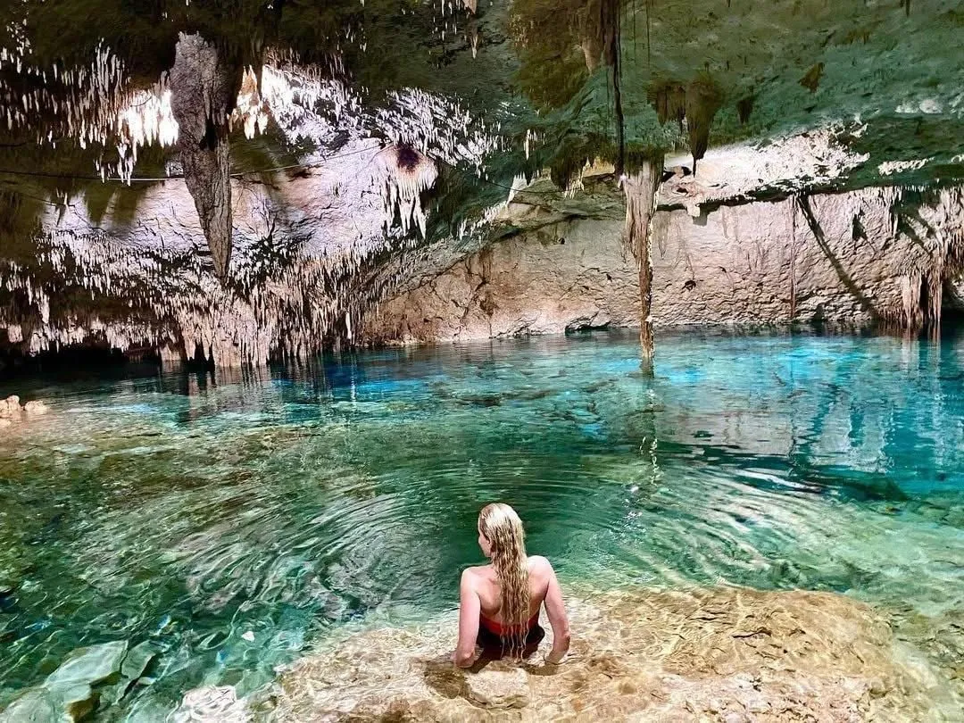 Woman swimming in the crystal-clear water of a cave cenote