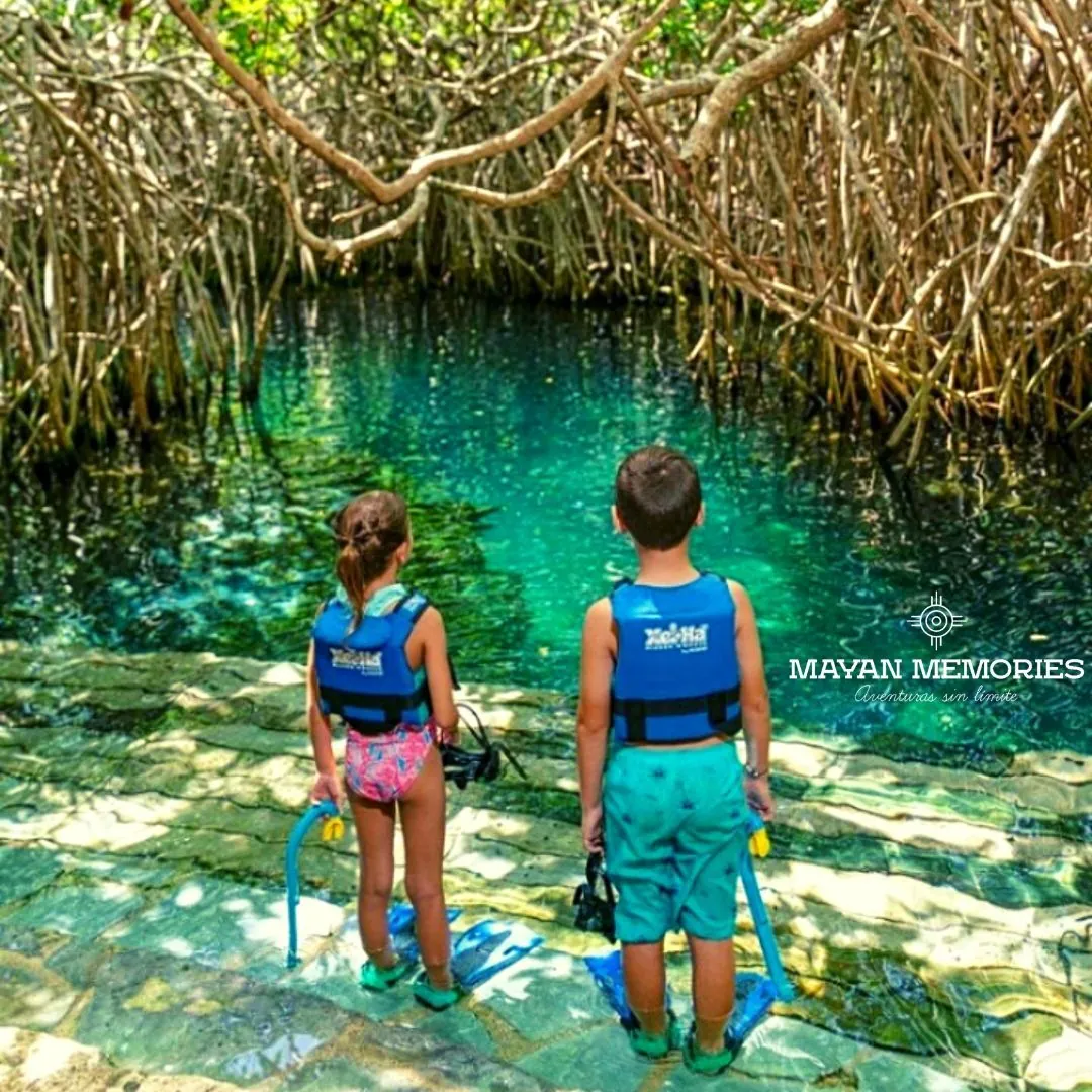 Two children in life jackets looking at a cenote in the jungle
