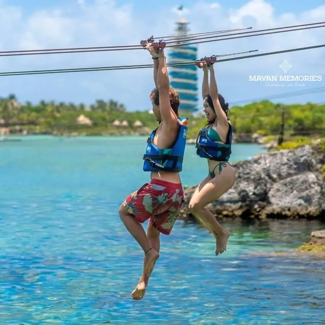Two visitors in life jackets hanging from a rope over the water
