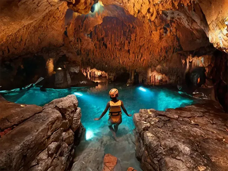 Swimmer in an underground river with glowing blue water