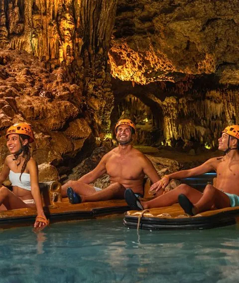 Couple in helmets paddling a raft inside a cavern
